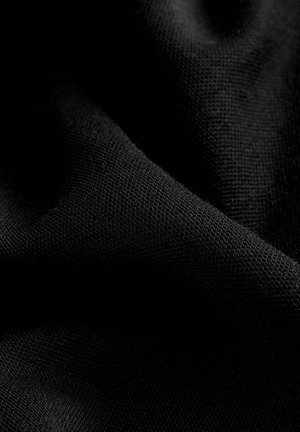 Melnā auduma ar teksturētu austu, redzamas mīkstas, drapētas krokas. Tam ir gluda virsma un dziļa, vienota krāsa.