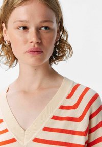 V-neck pullover sweater in cream with orange stripes. Soft knit texture, short sleeves, and ribbed neckline detail.