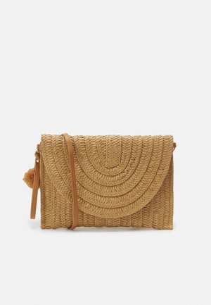 Sac à main en paille tressée de couleur beige, avec un rabat incurvé et un design texturé, comprenant une bandoulière détachable et un accent de pompon.
