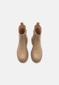 Botas de tobillo en tono marrón claro con un acabado suave, cremallera lateral, tira para facilitar el uso y suelas de goma gruesas. Presentan una puntera redondeada y detalles de costura.