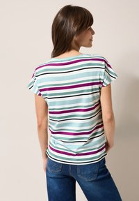 Stribet T-shirt i lyseblå med tynde og tykke striber i teal, mørkegrøn, lilla og sort. Korte ærmer og rund halsudskæring.