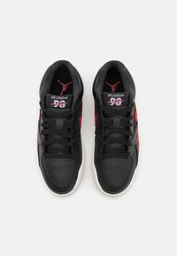 Schwarze und rote Air Jordan Sneakers mit einem perforierten Leder-Obermaterial, flachen Schnürsenkeln und einer weißen Gummisohle. Auffälliges Logo auf der Zunge.