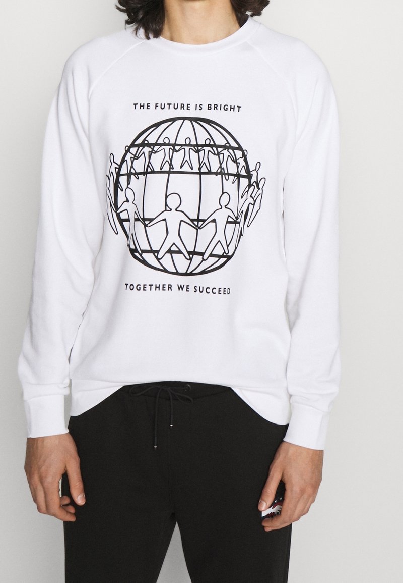 Sweat-shirt blanc avec un dessin au trait noir représentant des personnes interconnectées autour d'un globe et le texte « L'avenir est prometteur » et « Ensemble, nous réussissons. »