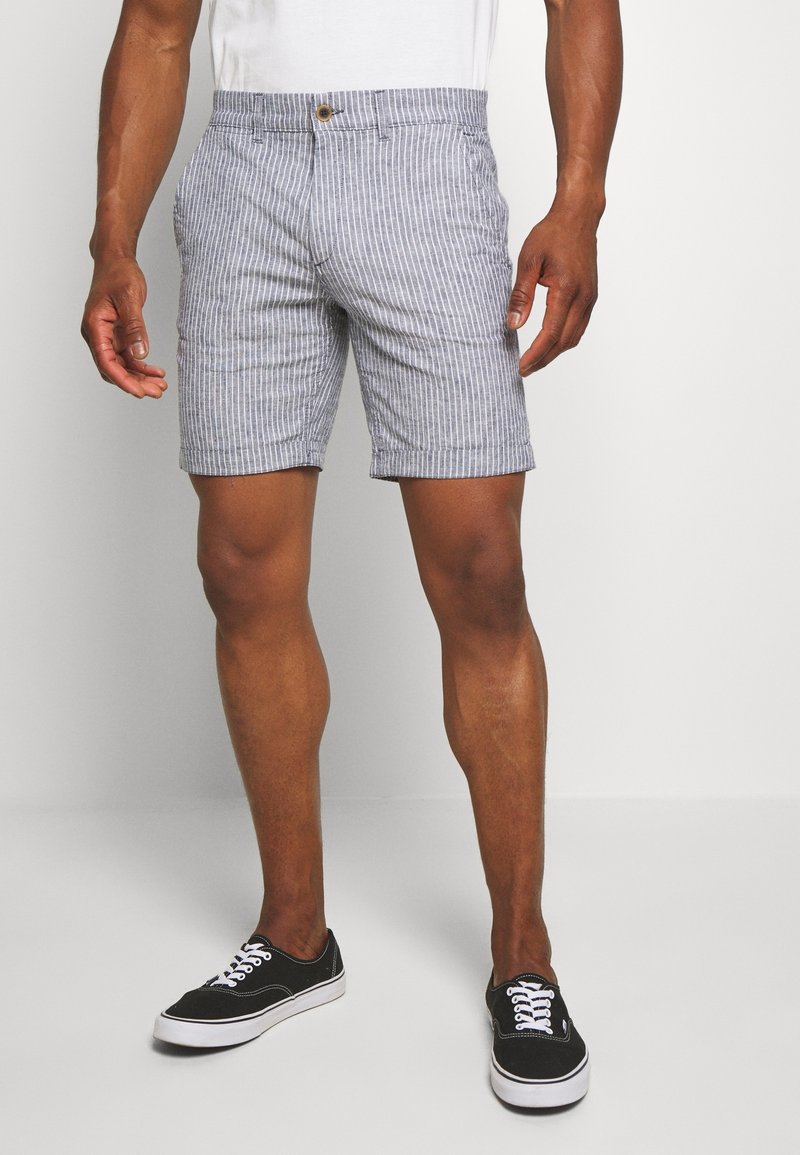 Pánské proužkované šortky vyrobené z lehké tkaniny; mají zapínání na knoflík, boční kapsy a rovný střih. Barva: modro-bílé pruhy.