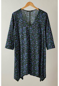 Schwarze Tunika mit V-Ausschnitt und 3/4-Ärmeln. Der Stoff zeigt ein florales Muster in Lila und Grün. Leicht verlängerter rückseitiger Saum.