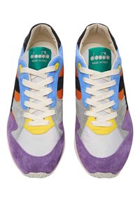 Une paire de baskets Diadora colorées avec des panneaux en suede violet, bleu, jaune, orange, gris et noir, et des lacets blancs, vue de dessus.