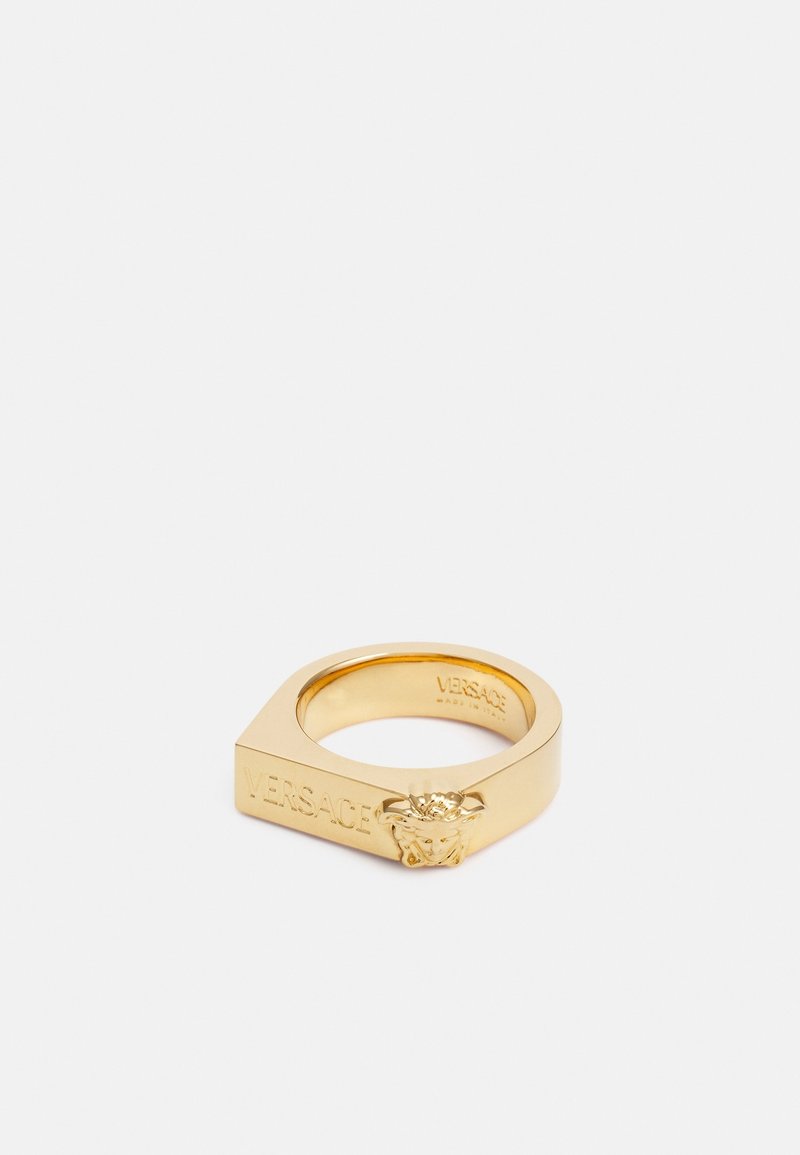Bague carrée en or avec un emblème tête de Méduse et "Versace" gravé sur le côté, présentée sur fond blanc.
