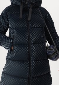 Kurtka puchowa w ciemnym niebieskim kolorze z wzorem w szachownicę, z kapturem, zamkiem z przodu i bocznymi kieszeniami. Teksturowany, gładki materiał z izolacją.