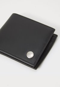 Portafoglio in pelle nera con una superficie liscia, dotato di inserto in metallo silver e logo, con bordi cuciti. Design pieghevole per una conservazione compatta.