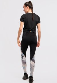 Maglietta atletica nera a maniche corte abbinata a leggings neri aderenti con un motivo colorato, caratterizzati da una vita testurizzata per un supporto migliore.