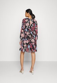 Vestido floral com mangas longas, fundo preto e flores coloridas em rosa e azul. Apresenta um decote em forma de olho-chave e uma bainha rodada.