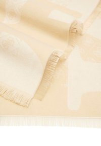 Coperta beige con una texture morbida, caratterizzata da un motivo sottile e bordi frangiati, che mette in mostra un mix di finiture lisce e tessute.