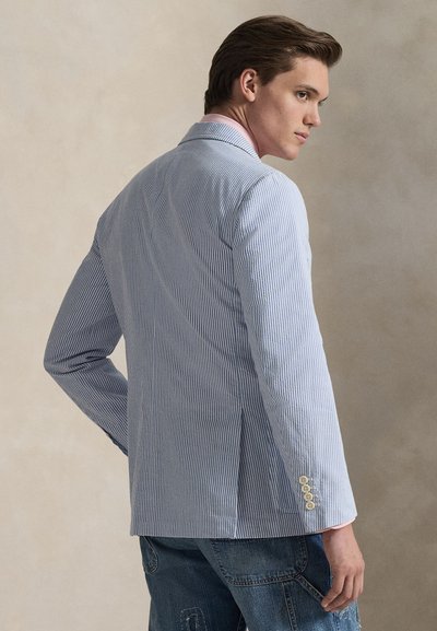 Prúžkované sako svetlomodrej a bielej farby, vyrobené z ľahkej látky. Má jedno rozparok, úzke klopy a manžety so zapínaním na gombíky. Neformálny štýl.