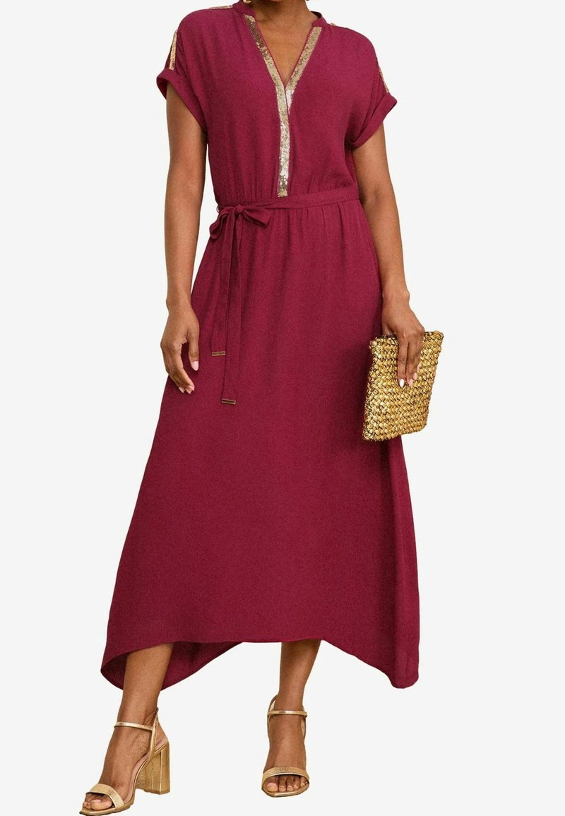 Burgundin pitkä mekko, jossa on lyhyet hihat, V-mallinen kaula-aukko ja kultaiset yksityiskohdat. Sidottu vyötärö ja korkea-alasolmuke. Yhdistetty tekstuuriseen kultaklutchin.