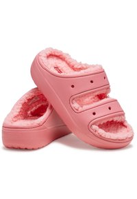 Różowe klapki na płaskiej podeszwie z futrzanym wnętrzem, wyposażone w dwie regulowane klamry, okrągły czubek oraz otwory wentylacyjne zapewniające oddychalność. Miękka tekstura całości.