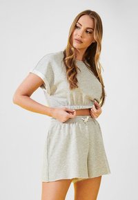 Gray cropped t-shirt and matching shorts made of soft fabric. The top has rolled sleeves, and the shorts feature an elastic waistband with drawstring.