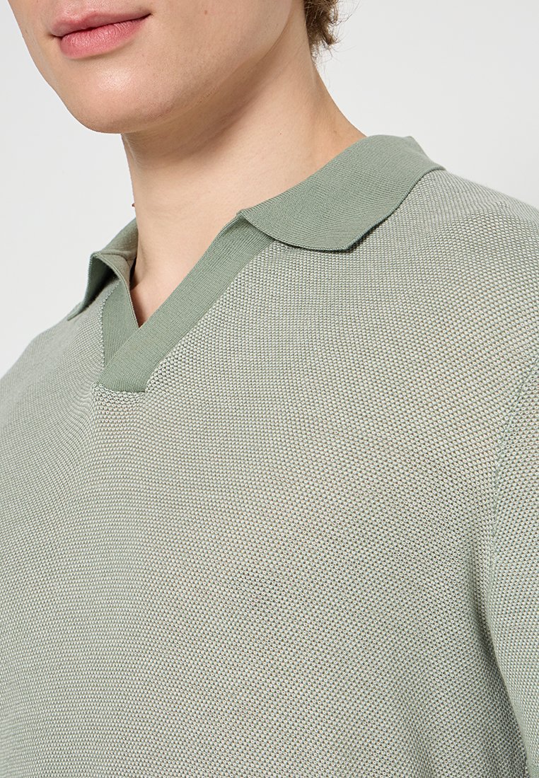 Hellgrünes gestricktes Poloshirt mit V-Ausschnitt und kurzem Kragen, ausgestattet mit einem strukturierten Stoffmuster und einem lässigen Schnitt.