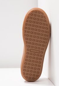 Semelle de chaussure en caoutchouc avec un motif texturé de petites étoiles. Présente une couleur brun clair et un logo de marque en relief. Design plat et légèrement incurvé.