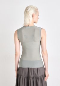 Top sans manches gris clair en matière transparente, présentant un design ajusté avec un col arrondi et des détails de couture subtils à l'ourlet.