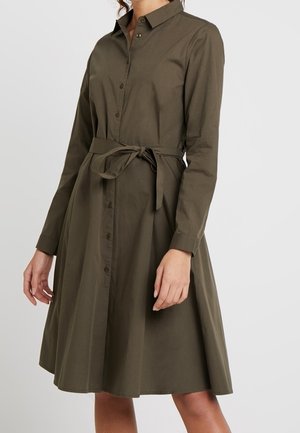 Vestido tipo camisa verde oliva con mangas largas, cuello, botones en la parte delantera y un cinturón anudado en la cintura. Tela de algodón suave.