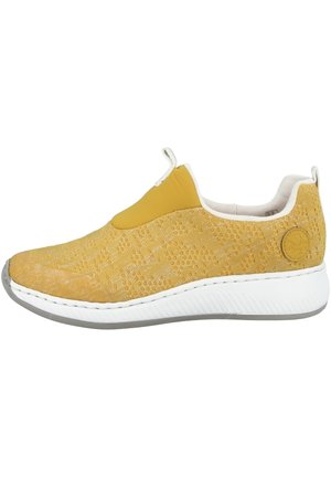 Żółty sneaker wsuwany o dzianinowej fakturze, z białą miękką podeszwą i pętelkami na języku oraz pięcie dla łatwego zakładania.