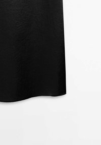 Black dress made of textured fabric, featuring a loose, flowy design with a round hem and minimal detailing. Smooth surface with subtle creases.