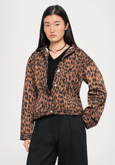 Prindi leopardi jakk, mis on valmistatud pruuni ja musta kangast, omades lühendatud disaini, nööbid ja krae. Kantud musta toppi ja pükste kanssa.