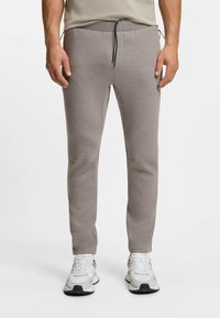 Hellgraue Jogginghosen mit elastischem Bund, Kordelzug und schlanker Passform. Hergestellt aus weichem, strukturiertem Stoff mit Seitentaschen.