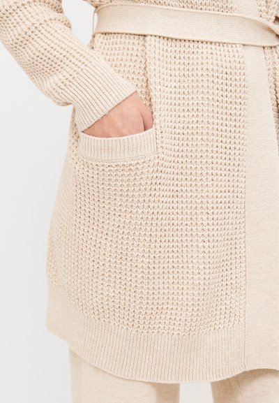 Knit cardigan in beige with textured fabric, featuring a belted waist and front pocket. Ribbed cuffs and smooth hem finish.