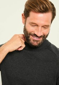 Dunkelgrauer Pullover mit hohem Kragen, aus weichem Stoff gefertigt. Verfügt über gerippte Bündchen und Schulternähte, die eine figurbetonte Optik erzeugen.