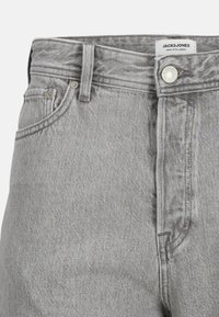 Pantalon en denim gris �à coupe droite, doté de passants de ceinture, d'une fermeture à bouton et de poches avant. Le tissu présente un aspect texturé et tissé.