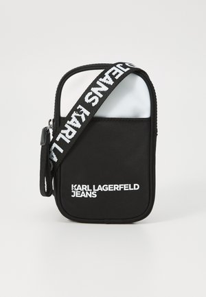Zwarte rechthoekige tas met een witte bovenkant, voorzien van een logo en vetgedrukte tekst. Heeft een ritssluiting en een verstelbare schouderriem met opdruk.