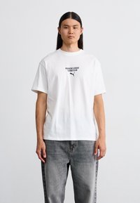 Hvid bomulds t-shirt med en sort grafisk tekst "Porsche League Turbo Club" og et Puma logo, med løs pasform og korte ærmer.
