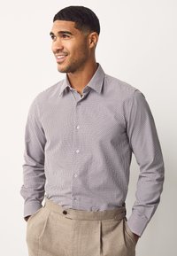 Chemise à manches longues boutonnée avec un petit imprimé blanc et marine. Tissu en coton avec un col structuré et des manches à poignets.