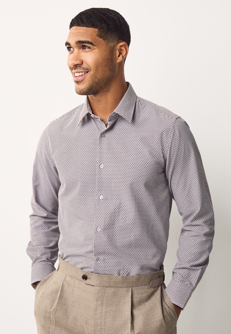 Chemise à manches longues boutonnée avec un petit imprimé blanc et marine. Tissu en coton avec un col structuré et des manches à poignets.