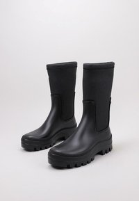 Bottes de pluie en caoutchouc noir avec un haut tige, semelles texturées et bout rond. Panneaux latéraux pour un enfilage plus facile et une adhérence robuste.