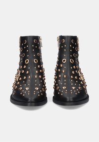 Botas de tobillo de cuero negro con tachuelas en tono dorado, que cuentan con un cierre de cremallera y una punta redondeada, diseñadas con un patrón de tachuelas en toda la superficie.