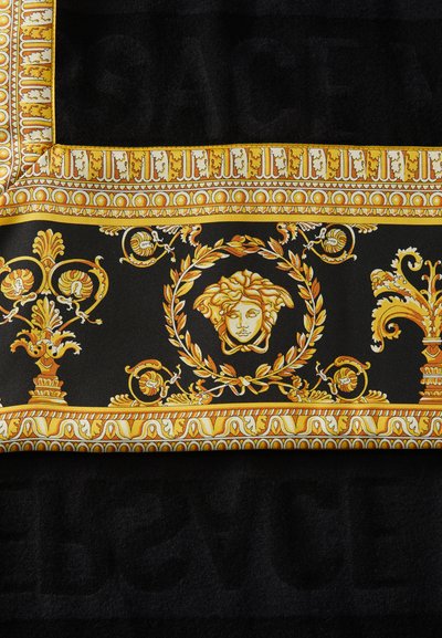 Czarna tkanina z ozdobnym złotym wzorem zawierającym misternie wykonane motywy, wieniec laurowy oraz centralny motyw twarzy. Obramowania są bogato zdobione.