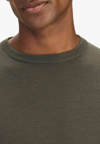 Khaki grön stickad tröja med rund halsringning och ribbat avslut. Slät textur med en figurnära silhuett. Inga synliga mönster eller dekorationer.