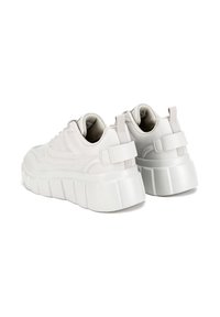 Zapatillas de plataforma blancas con parte superior texturizada y lisa y forro suave. Suela de goma gruesa con diseño acanalado. Incluye correa ajustable en el talón.