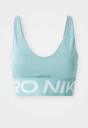 Svijetloplavi sportski grudnjak s izrezom u obliku suđenja, širokim trakama i elastičnom trakom s brendom koja sadrži "NIKE" u debelim bijelim slovima. Glatka tekstura tkanine.