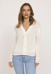 Cardigan blanc en tricot avec un col en V, un devant boutonné et des poignets côtelés. Des accents de rayures rouges au niveau de l'ourlet et des poignets ajoutent un contraste.