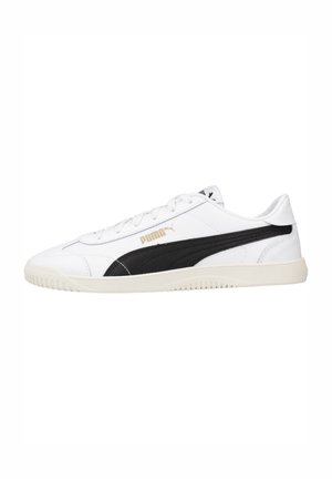 Zapatillas blancas de cuero con una franja acentuada en negro, laterales texturizados, punta redonda y suela de goma color crema. Logo en dorado en el lateral.