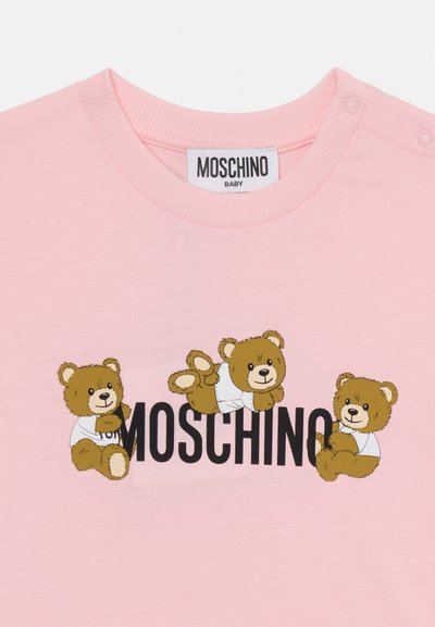 Rožinė medvilninė marškinėliai su trimis animaciniais lokiais baltais marškiniais, žemiau lokių juodu šriftu užrašas "MOSCHINO".