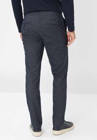 Marineblauwe broek met een slim fit, gemaakt van een gestructureerde stof, met twee achterzakken met knopen en een taps toelopende pijp.