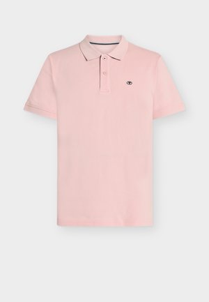 Light pink short-sleeve polo shirt with two buttons and small black logo on the left chest on a plain background.