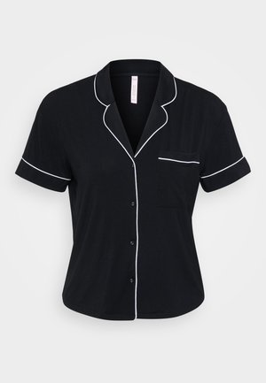 Black short-sleeve blouse with white piping along the collar, sleeves, and pocket. Features a button closure and soft fabric texture.