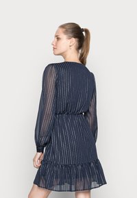 Vestido azul-marinho com riscas verticais prateadas, mangas longas transparentes, cintura ajustada e barra em folhos. Textura suave, design elegante.