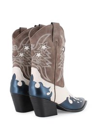 Botas de cowboy de ante marrón con acentos en blanco y azul, bordado de estrellas, un diseño curvado y un tacón negro grueso.