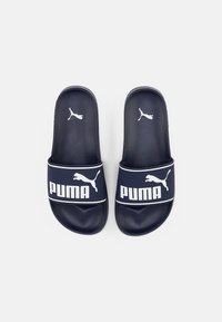 Sandales à glissière bleu marine avec une large bride présentant une surface texturée et le logo "PUMA" blanc ainsi qu'un petit emblème logo. Semelle lisse et plate.